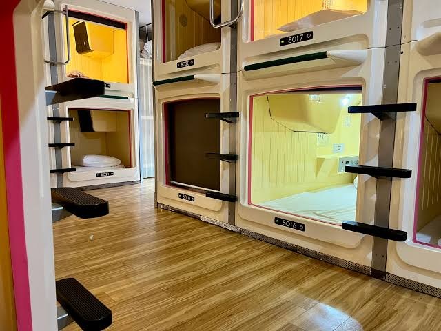 Stacked capsule berths on a shared floor at a capsule hotel in Shinjuku, Tokyo